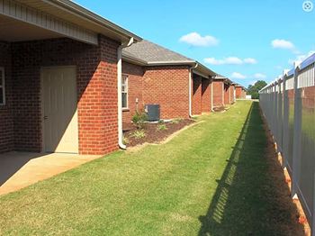 A long row of houses with a green lawn in between.